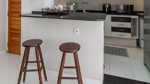 A modern kitchen with a central island, two wooden stools, and stainless steel appliances. - Acogedor Rinc n en Ipanema Ac2002 (Rio de Janeiro)