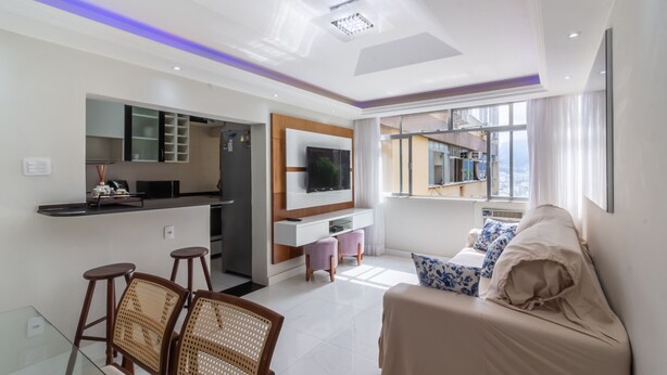 A modern living room with a sofa, a TV, and a kitchen area with a bar. - Acogedor Rinc n en Ipanema Ac2002 (Rio de Janeiro)