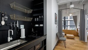 A modern kitchen with black cabinetry, stainless steel appliances, and a pegboard wall with kitchen utensils. - 3 Units | Family Stay in NYC w/Kitchen | Near Top Landmarks & Vibrant Dining (New York)