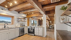 A spacious kitchen with white cabinetry, a built-in oven, and a large window overlooking a scenic view.