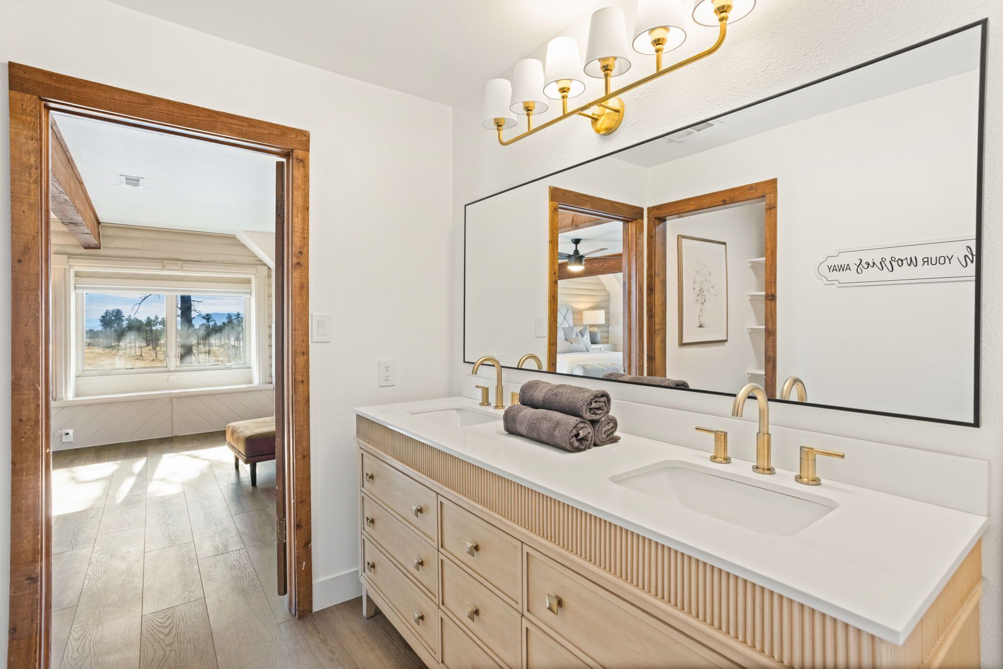 A modern bathroom with a large mirror, two sinks, and a vanity with drawers.
