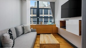 A modern living room with a grey sofa, wooden coffee table, and a large TV mounted on the wall. - 2 Units | Modern NYC Apartment | Perfect for Long Stays & Manhattan Adventures (New York)