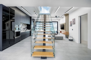 Eine moderne Küche mit einer gläsernen Wendeltreppe, die zu einem Wohnbereich führt.