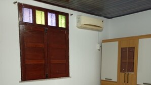 Een kamer met twee eenpersoonsbedden, een houten garderobe, een raam met glas-in-lood en een airconditioning.