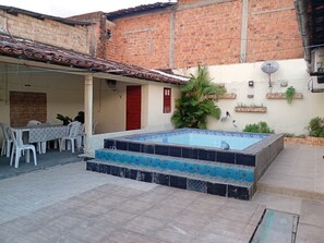 Une piscine avec des marches menant à l’eau, entourée d’une terrasse aménagée avec une table et des chaises.