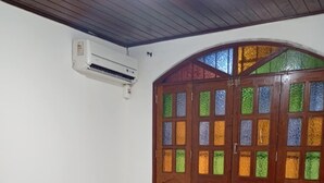 Een kamer met twee bedden, een houten plafond en een raam met kleurrijk glas-in-lood.