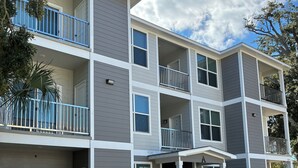 A multi-story residential building with balconies, large windows, and a brick-paved entrance. - Sunny Daze 1 Bed Apt. (Biloxi)