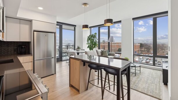 Una cocina moderna con una isla central, electrodomésticos de acero inoxidable y amplios ventanales con vistas a la ciudad.