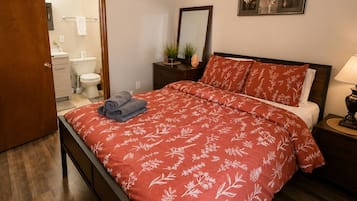 A bedroom with a wooden bed, a bedside table with a lamp, a mirror, and a wall-mounted picture.