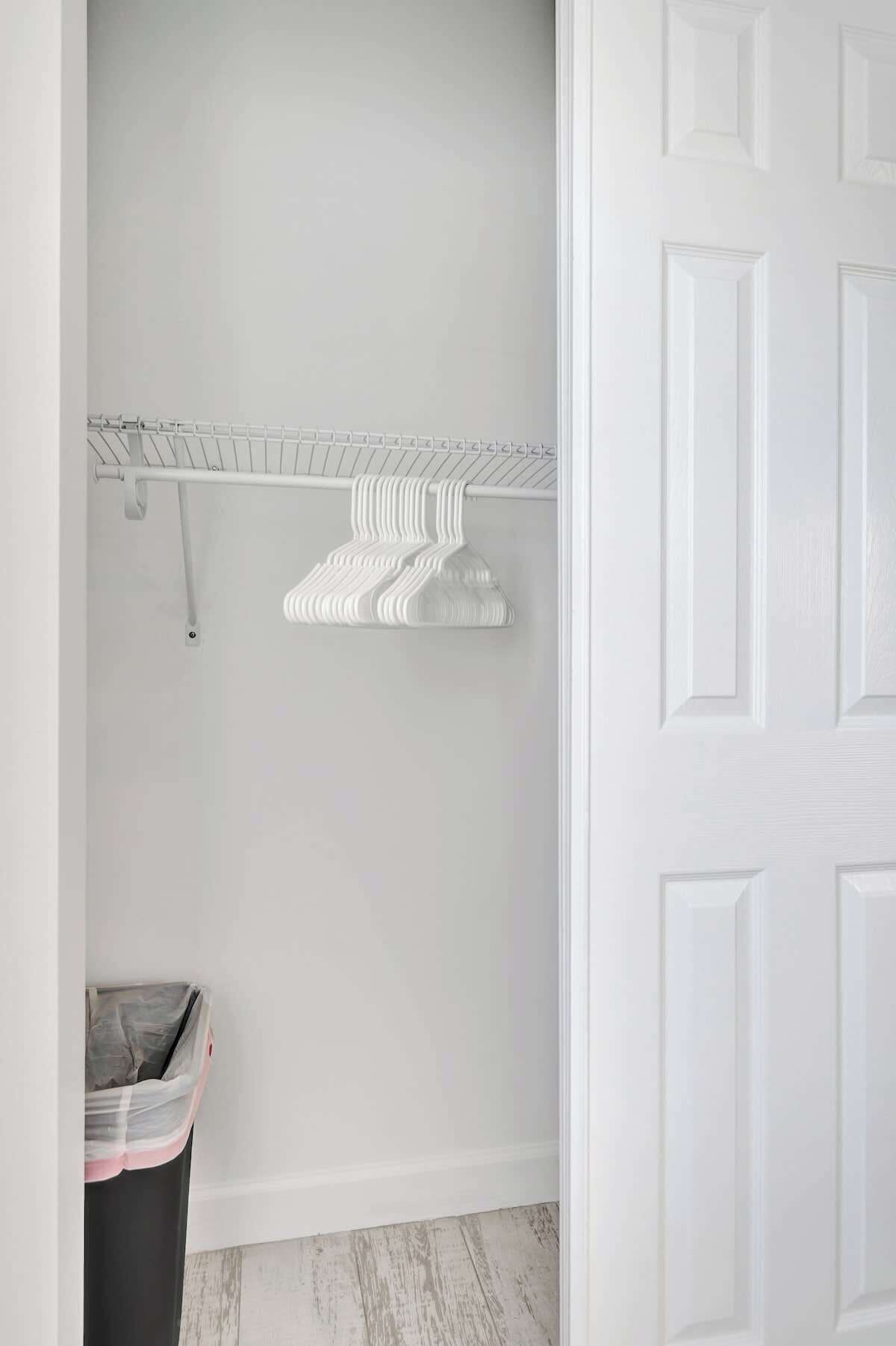 A white closet with a metal shelf holding folded clothes.
