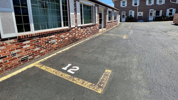 Un parcheggio con un edificio in mattoni e una struttura a due piani sullo sfondo.