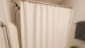 Un bagno con doccia, WC e maniglione.