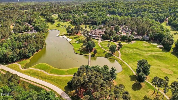 Oversigtsbillede af en golfbane med flere søer, omgivet af tætte skove og boligområder.