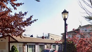 A motel with a red car parked in front, a street lamp, and a clear sky. - Cozy 1BR End Cottage W/D • Parking •Walk to Train (Swarthmore)