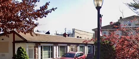 Un motel con un coche rojo estacionado adelante, una farola y un cielo despejado.