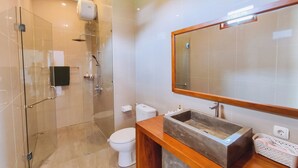 Une salle de bain moderne avec une douche à parois de verre, des toilettes et un meuble-lavabo doté d’un grand miroir.