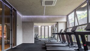 Un gimnasio con cintas de correr, bicicletas estáticas y un muro de cristal que ofrece vistas al exterior.