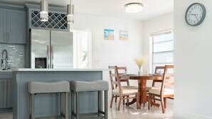 Una cocina moderna con electrodomésticos de acero inoxidable, una zona con taburetes de bar y una mesa de comedor con sillas.