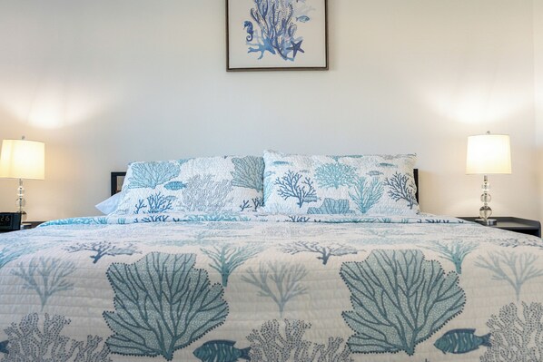 A bed with a blue and white coral pattern bedspread, two bedside lamps, and a framed coral artwork on the wall. - Ocean Pearl•Hudson Beach•Gulf Access•Pets Welcome (Hudson)