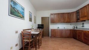 Eine Küche mit Holzausstattung, einem Esstisch mit Stühlen und einem Fernseher an der Wand.