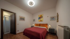 Ein Schlafzimmer mit einem Bett, einem Nachttisch, einem Heizkörper und einer Tür zu einem Badezimmer.