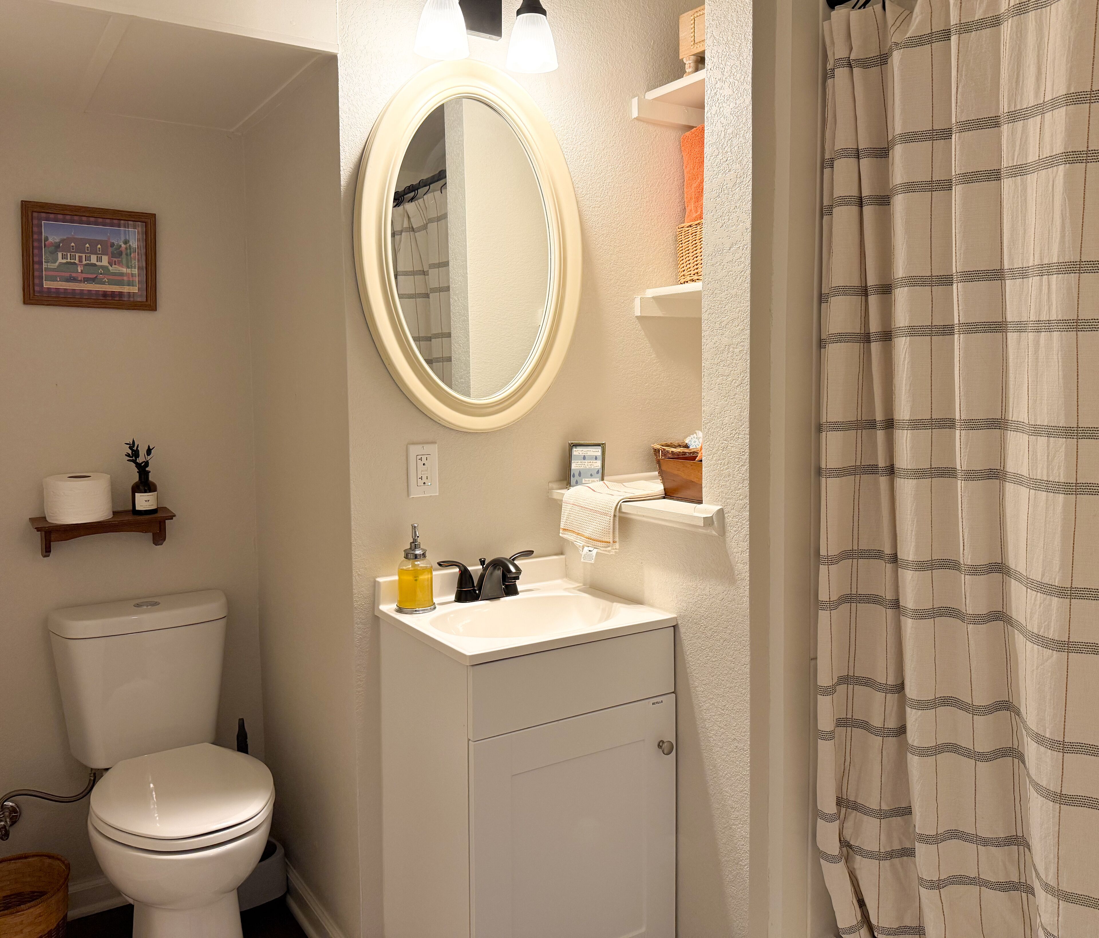 A bathroom with a toilet, sink, mirror, and shower curtain.