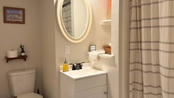 A bathroom with a toilet, sink, mirror, and shower curtain.