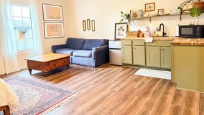 Un salon comprenant un canapé, une table basse et un coin cuisine équipé d’un four à micro-ondes et d’un réfrigérateur.