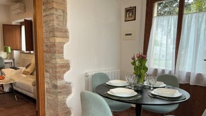 Een eetruimte met een bakstenen zuil, een tafel gedekt voor vier personen en lichtblauwe stoelen.