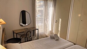 Ein Hotelzimmer mit einem Bett, einem Schreibtisch, einem Stuhl, einem Spiegel und einem Kleiderschrank.