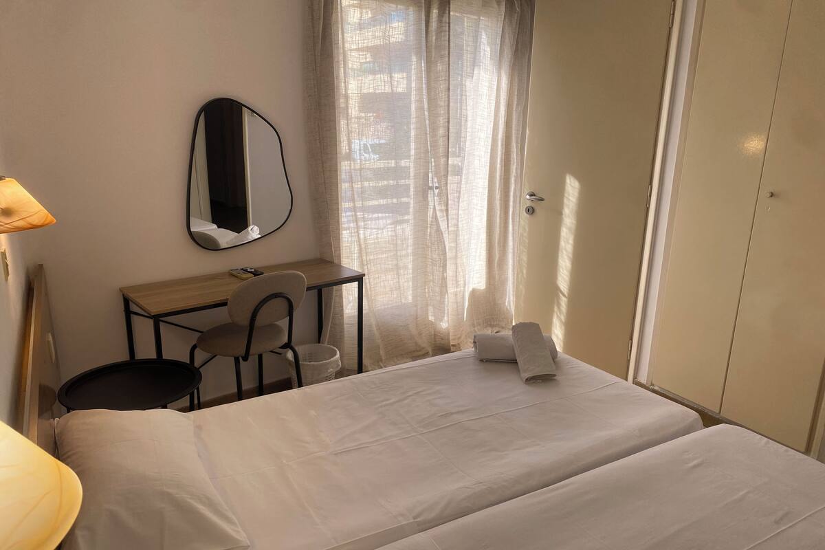 Een hotelkamer met een bed, een bureau, een stoel, een spiegel en een kledingkast.