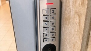 Eine Tastatur-Zimmertürschloss mit roter Leuchtanzeige, einem Zahlenschlüssel und einem Klingelknopf.