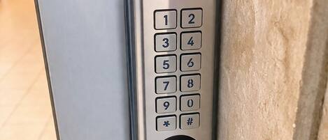 A keypad door lock with a red light indicator, a numeric keypad, and a bell button.