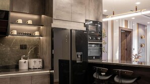 A modern kitchen with stainless steel appliances, a wooden countertop, and a bar area with stools. - Luxury apartment with pool, gym & games (Lekki)
