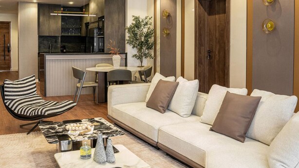 A modern living room with a sofa, a striped chair, a coffee table, and a hanging light fixture. - Luxury apartment with pool, gym & games (Lekki)