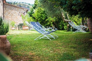 Un jardín con dos sillones blancos y un muro de piedra.