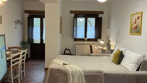Ein Schlafzimmer mit Bett, Nachttisch, Lampe und einem Fenster mit Vorhängen.