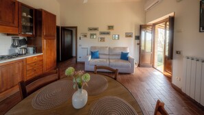 A spacious living area with a dining table, wooden cabinets, and a sofa with blue cushions. - Farmhouse Il Mulino delle Canutole - Pienello (Magione)