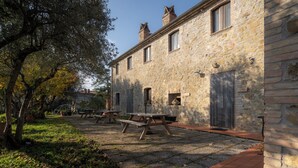 A stone building with a patio area, outdoor seating, and a tree. - Farmhouse Il Mulino delle Canutole - Pienello (Magione)