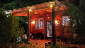 Eine Holzjagdhaushälfte mit überdachter Veranda, einem Ziegelweg, der zum Eingang führt, und einem Hund in der Nähe.