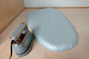 A portable electric iron with a blue pad, a power cord, and a control button.