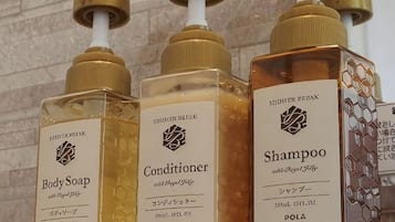 Tres botellas de productos para el baño: jabón corporal, acondicionador y champú.