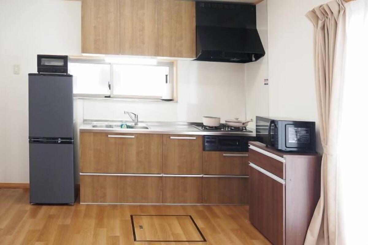 A kitchen with wooden cabinets, a refrigerator, a microwave, and a stove.