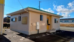 A small, single-story building with a flat roof, a door, and windows. - Western-style house for families and groups (Okuma)