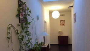 A hallway with a potted plant, a lamp, and a framed picture on the wall. - Hotel Feiertag (Pforzheim)