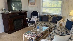 Un salon confortable avec une cheminée, un ensemble de canapés, un téléviseur et un ventilateur de plafond.