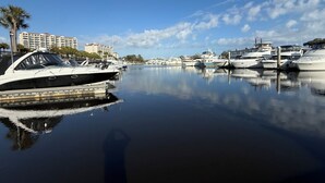 Un port de plaisance avec des bateaux amarrés, un ciel dégagé et un bâtiment en arrière-plan.
