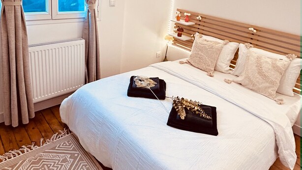 Un dormitorio con una cama grande, un cabecero de madera, un tapete estampado y una ventana con cortinas.