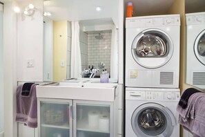 Ein modernes Badezimmer mit Waschbecken, Spiegel und gestapelten Waschmaschinen.