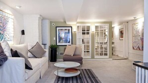 Een moderne woonkamer met een witte bank, een ronde salontafel en een gestreept vloerkleed.